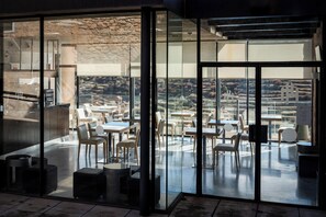 A modern dining area with glass walls, a stone wall, and a view of the countryside. - Hotel Hospedería Palacio de Allepuz (Allepuz)