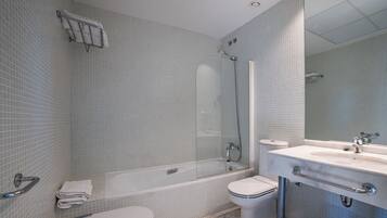Ein modernes Badezimmer mit einer Duschkabine aus Glas, einer weißen Badewanne, einer Toilette und einem Waschbecken mit Spiegel.