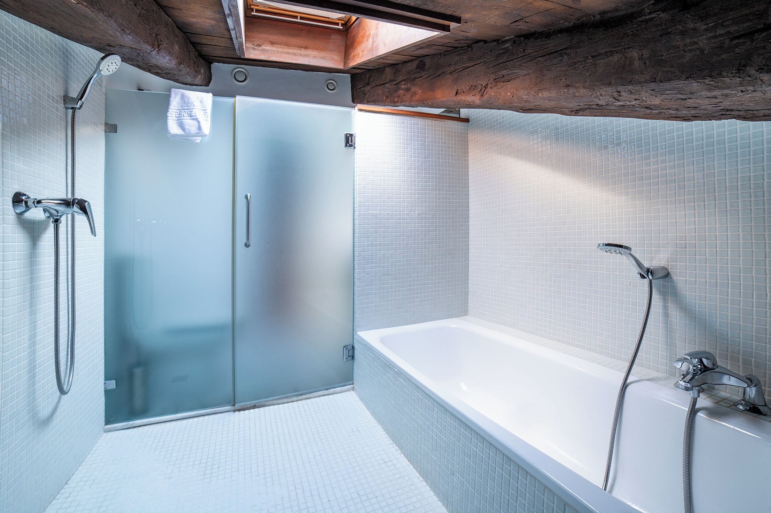 A modern bathroom with a glass shower enclosure, a freestanding bathtub, and tiled walls.