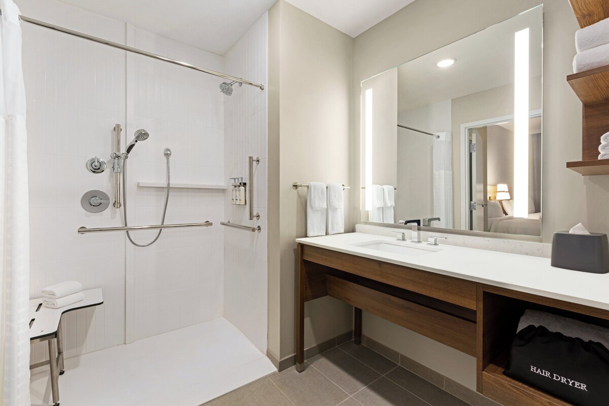 A modern bathroom with a walk-in shower, a vanity with a mirror, and a towel rack.
