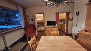 Una habitación con cama, escritorio, televisor, ventana con vistas a un edificio y un radiador.