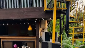 Ein Außenbereich mit Tisch und Stühlen, einem Neonzeichen und einem Blumentopf.