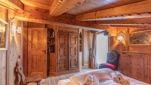 Quarto de madeira com uma cama, uma cadeira e um guarda-roupa.