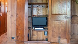 Uma estante de madeira com uma televisão, prateleiras embutidas e um arco decorativo.