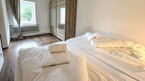 Une chambre avec deux lits, une fenêtre avec des rideaux, un radiateur et une armoire.