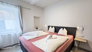 A neatly made double bed with white linens, a bedside table with a lamp, and a window with sheer curtains. - Beautiful apartment for 6 guests with WIFI, TV and pets allowed (St Michael Im Lungau)