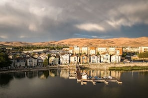 A lakeside residential area with houses, a dock, and a mountain backdrop.