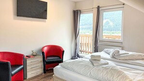 A bedroom with a bed, a red chair, a small table, and a window with curtains. - Nice apartment for 4 people with WIFI, balcony and pets allowed (St Michael Im Lungau)