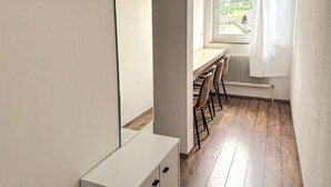 A compact room with a wooden desk, a chair, a radiator, and a window with a view of greenery. - Nice apartment for 4 people with WIFI, balcony and pets allowed (St Michael Im Lungau)
