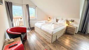 A bedroom with a large bed, a desk with a red chair, a nightstand, and a window with curtains. - Nice apartment for 4 people with WIFI, balcony and pets allowed (St Michael Im Lungau)