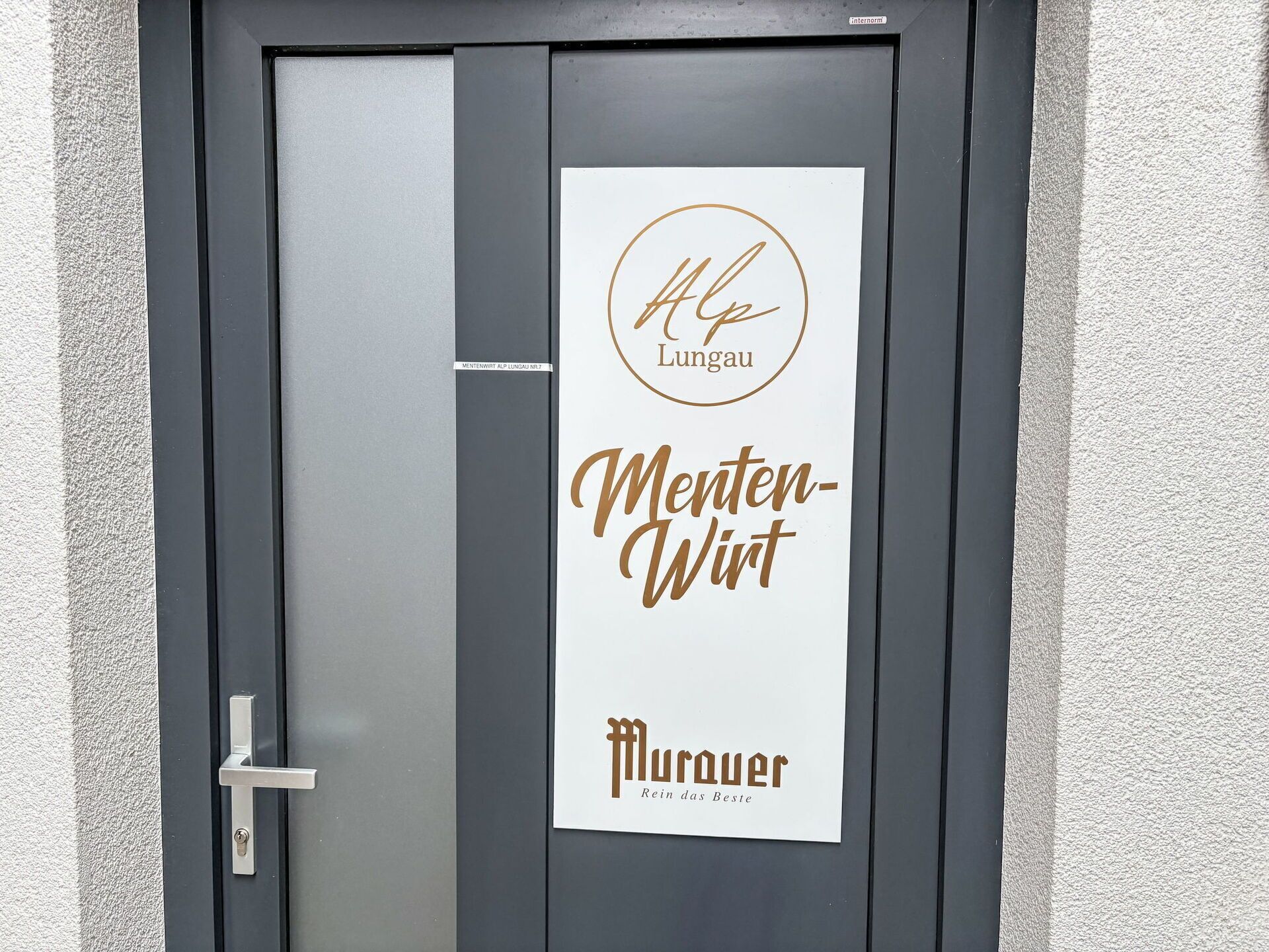En dörr med en skylt som visar texten ”Alp Lungau Menten-Wirt” och ”Murauer Rein das Beste”.