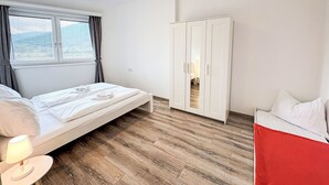 Een slaapkamer met een bed, een nachtkastje, een kledingkast en een raam met gordijnen.