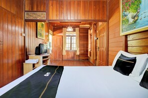 Ein Zimmer mit Holzboden, einem Bett, einem Fernseher und einem Bild an der Wand.