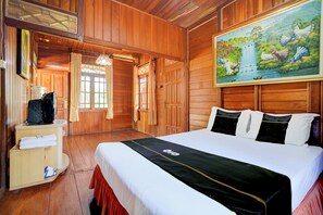 Ein Zimmer mit Holzboden, einem Bett, einem Fernseher, einem Wasserspender und einem Vogelbild.