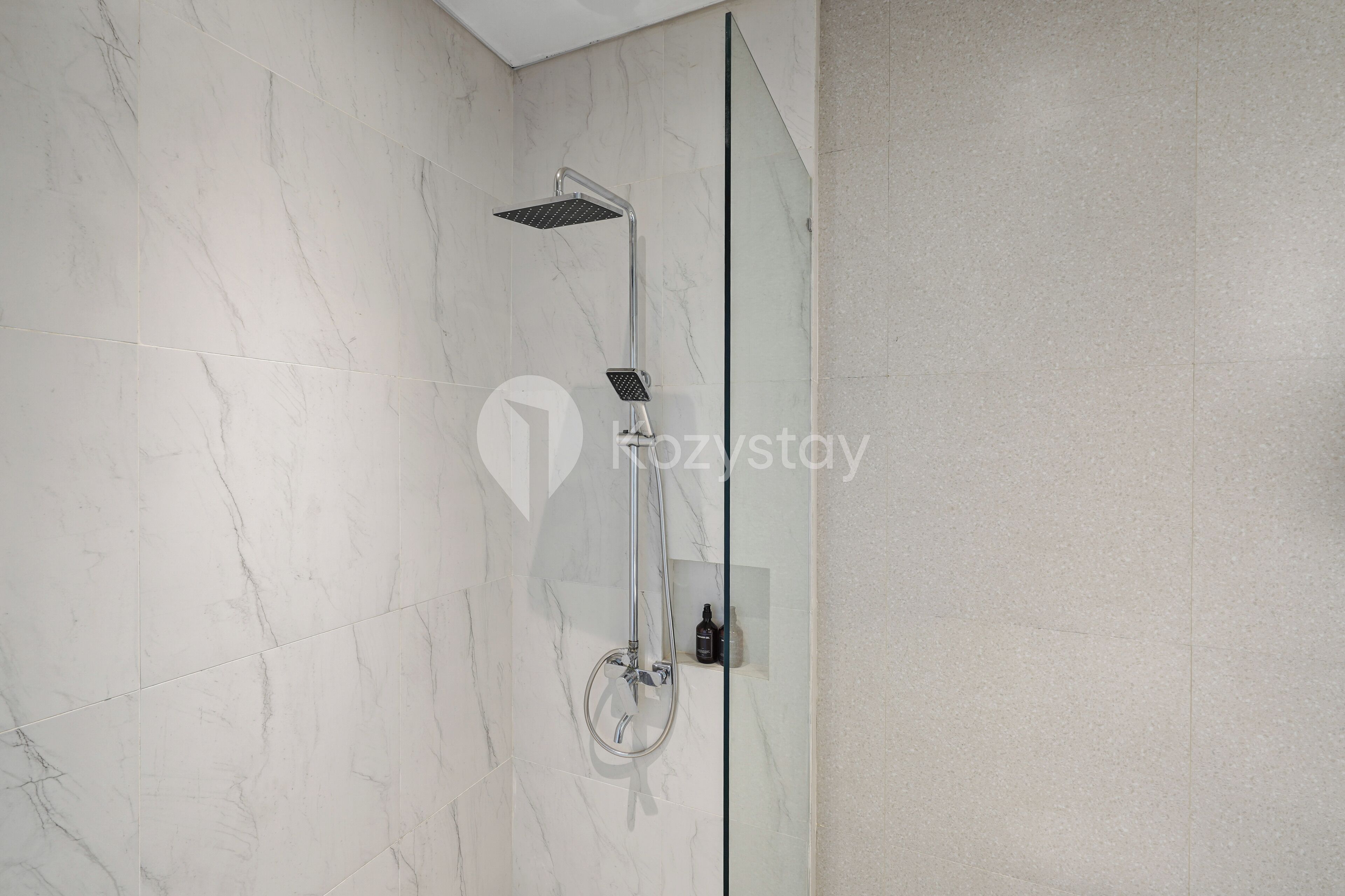 A modern bathroom with a glass shower enclosure, marble tiles, and a minimalist design.