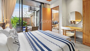 A modern bedroom with a large bed, a desk, and a bathroom.