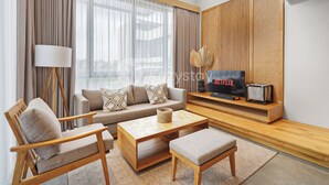 A modern living room with a sofa, armchairs, a coffee table, and a TV on a wooden stand.