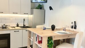 Una cocina moderna con armarios blancos, horno integrado y una mesa de comedor de madera con sillas.