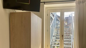Una habitación con un ventanal grande, un armario de madera y un televisor instalado en la pared.