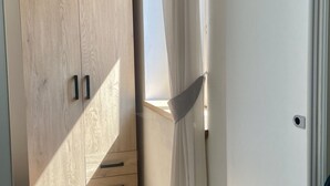 Una habitación con un armario de madera, una puerta blanca y una ventana con cortinas.