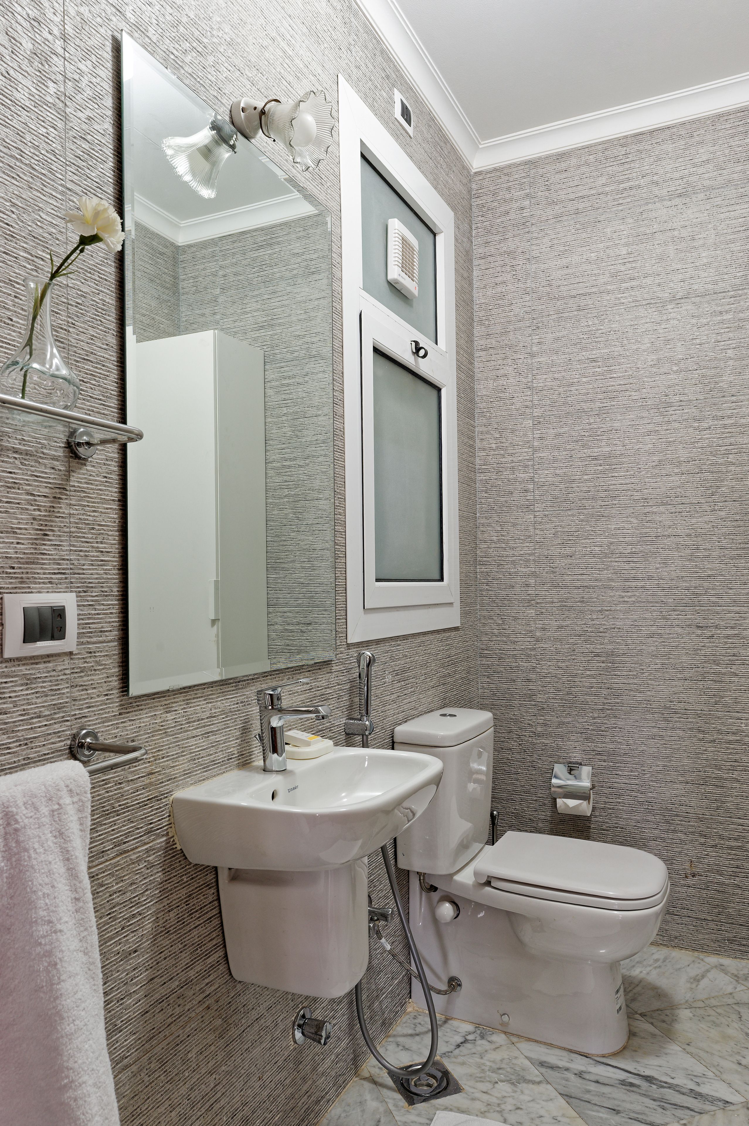 Een badkamer met een grote spiegel, een wastafel, een toilet en een handdoekhouder.