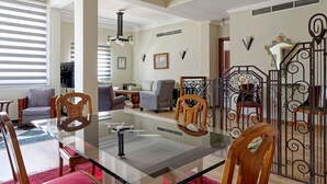 A dining area with a glass table, wooden chairs, and a red carpet.