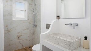 A bathroom with a shower, toilet, and a sink with a marble countertop. - Deluxe Suite, Palma Elegant Suites (Paros)
