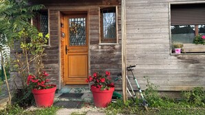 Una casa de madera con puerta principal, dos ventanas y un pequeño porche.