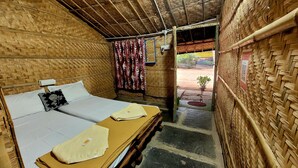A room with a bed, a wooden ceiling, and a door leading outside.
