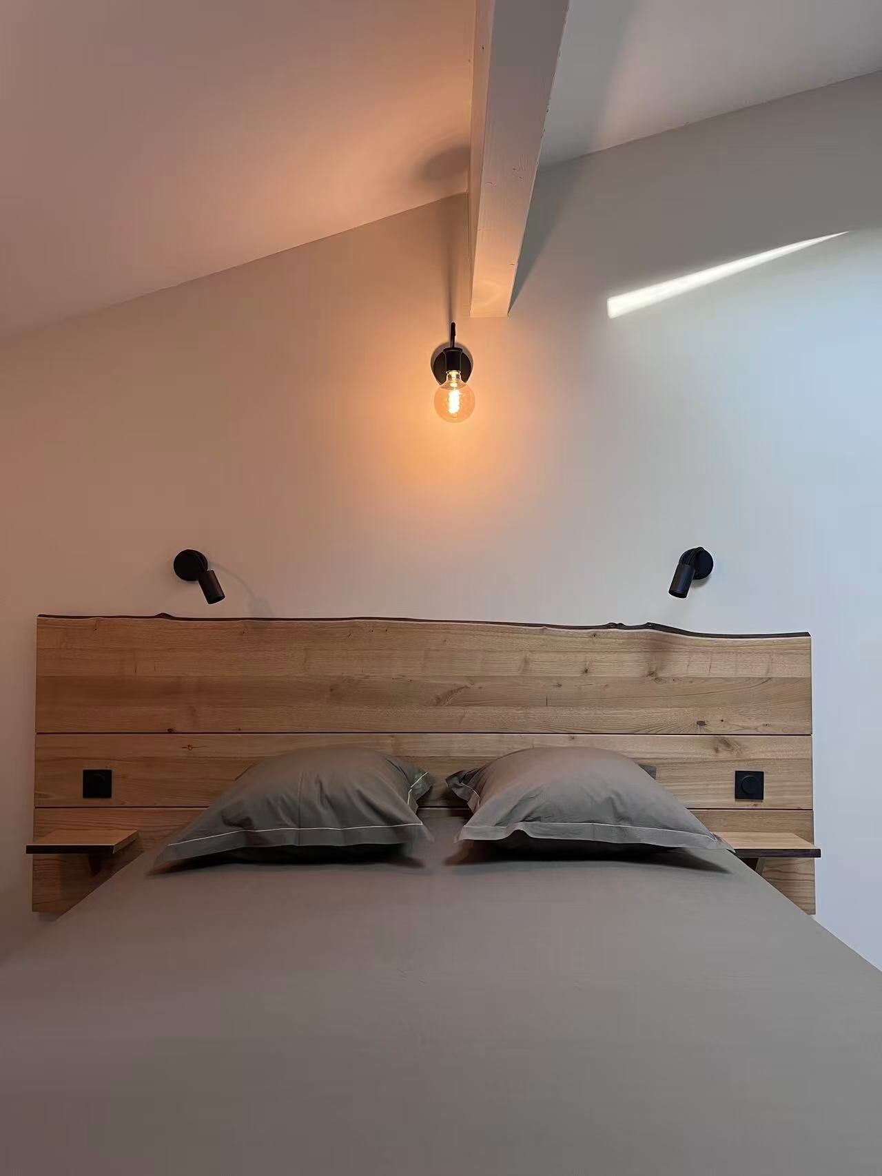 Un dormitorio con cabecera de madera, dos lámparas de noche y una bombilla colgando del techo.