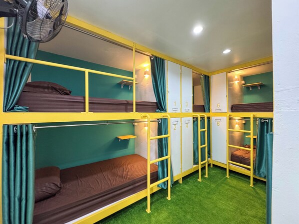 A bunk bed room with green walls, yellow railings, and a ceiling fan. - Banana Bunkhouse Hostel (Rawai)