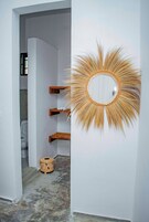 A hallway with a decorative sunburst mirror and wooden shelves.