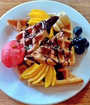 Une assiette avec des gaufres, des fruits et une boule de glace.