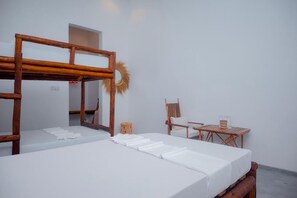A room with a bunk bed, a small table with a chair, and a mirror on the wall.