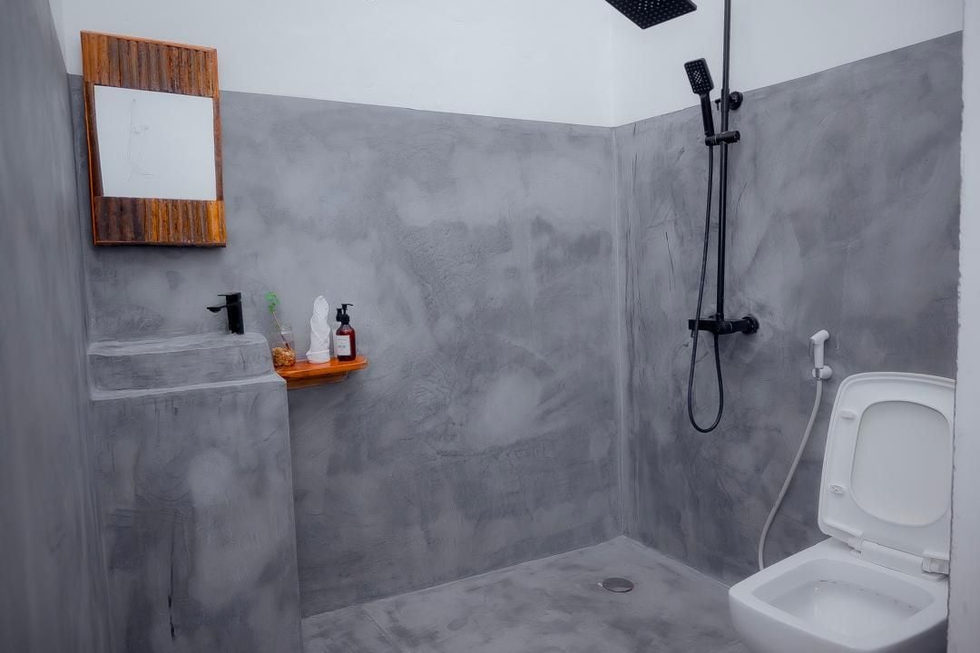 Casa de banho com chuveiro, sanita e um prateleira com artigos de higiene pessoal.