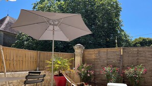 An outdoor patio with a table, chairs, an umbrella, and potted plants.