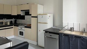 A compact kitchen with a dishwasher, a refrigerator, a microwave, and a stove.