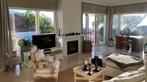 A spacious living room with a fireplace, a television, and a comfortable seating area. - Villa Gecko (La Puntilla)