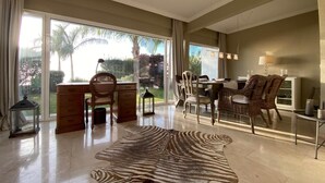 A spacious living room with a large window, a zebra print rug, and a dining area with wicker furniture. - Villa Gecko (La Puntilla)