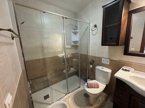 Ein Badezimmer mit Duschkabine, Toilette und Waschbecken.