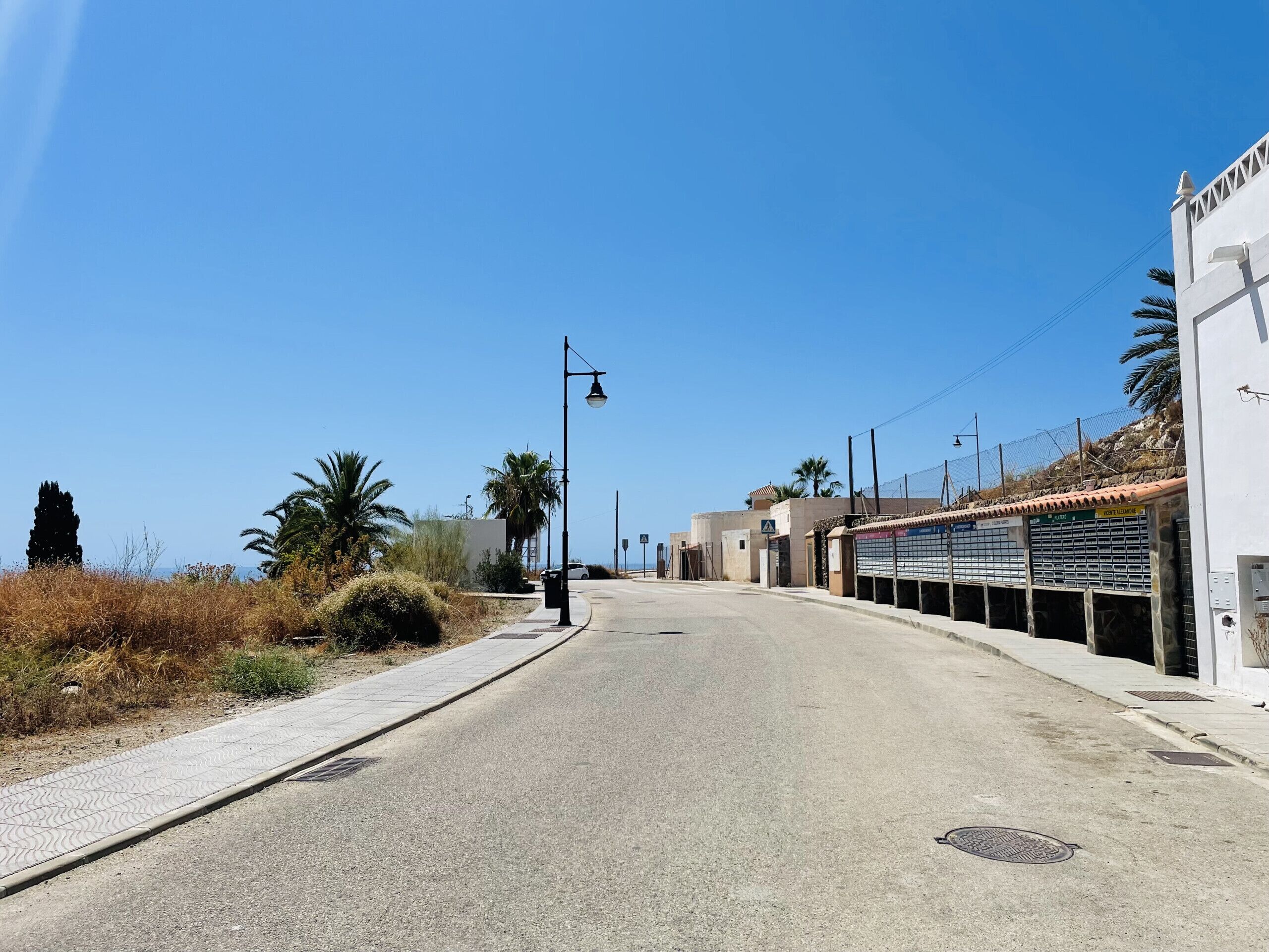 Una calle tranquila con acera, farol y un edificio con tejado de tejas.