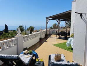 Eine Terrasse mit Meerblick, Gartenmöbeln und einer überdachten Sitzecke.