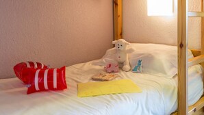 A bunk bed with a white mattress and pillows, a stuffed toy, a toy car, and a yellow envelope on the bed. - BLUE AIR-CONDITIONED STUDIO CABIN SLEEPS 4 (Sainte-Maxime)