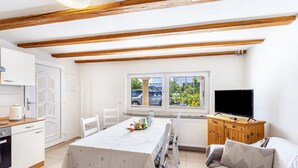 Een compacte leefruimte met een eethoek, kitchenette en een televisie.