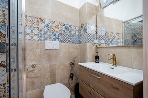 A bathroom with a shower, toilet, and vanity with a mirror. - Apartment 'Dimora Don Gabriele' with Balcony and Air Conditioning (Mola Di Bari)