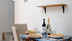 Una mesa de comedor con platos, vasos y botellas, una silla y una estantería en la pared.