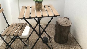 A small wooden table with a woven basket and a potted plant, a folding chair, and a wooden stump.