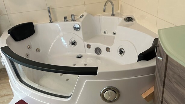 A modern bathroom with a freestanding bathtub, a vanity with a mirror, and a small statue on the wall.