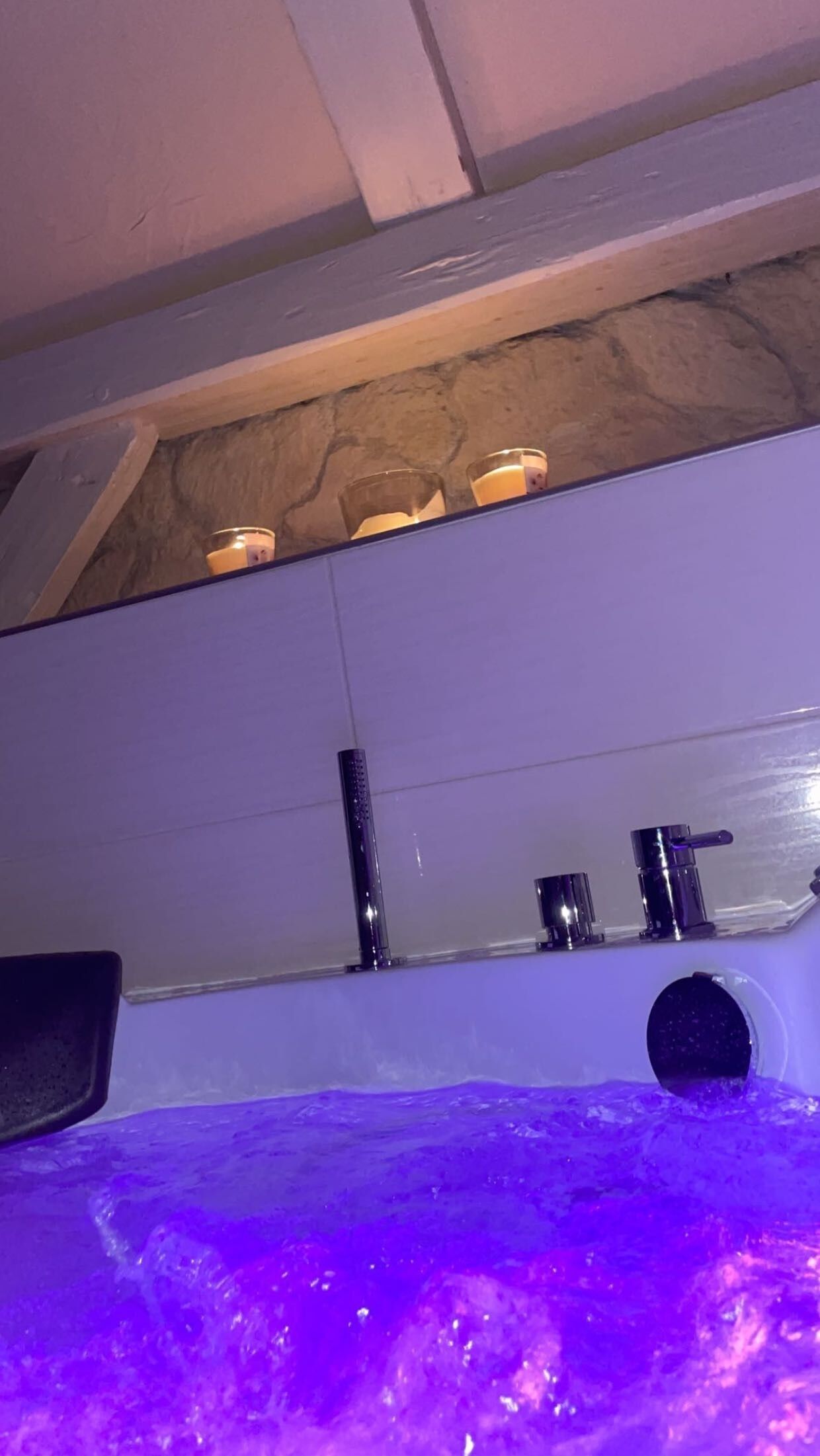 Ein Zimmer mit Badewanne, Dusche und einem Fenster zur Steinwand.