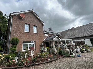 Ein zweistöckiges Ziegelhaus mit Garten, der Statuen und Blumen zeigt.